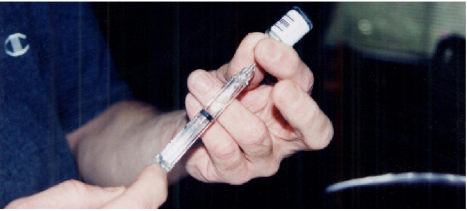 Hands preparing a prefilled syringe for a home injection