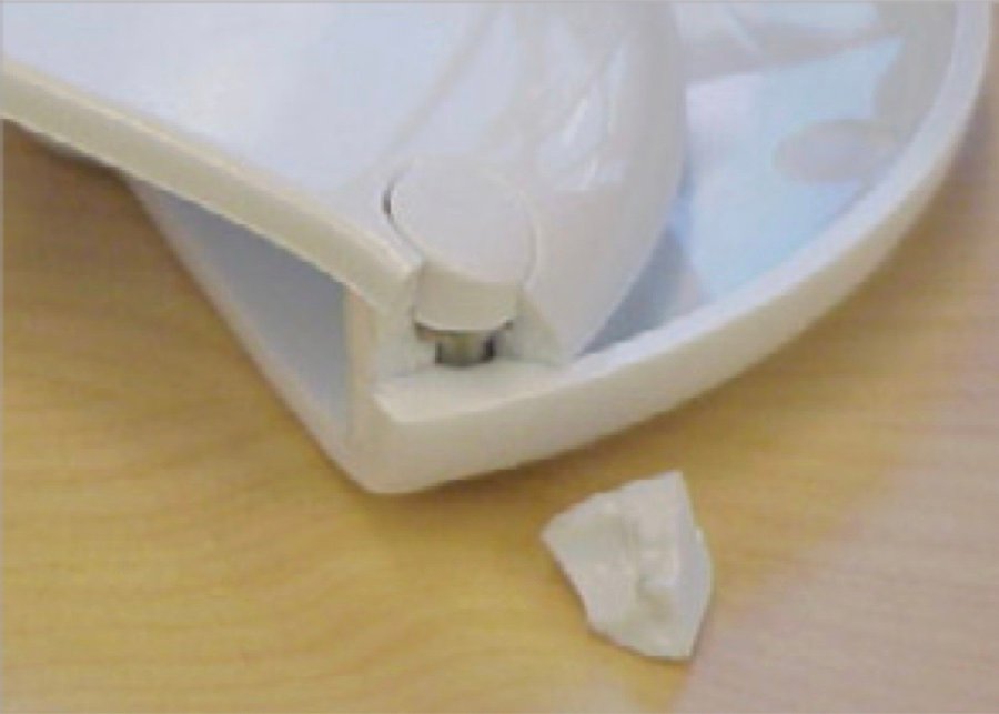 A white prototype garlic press with a small fragment beside it