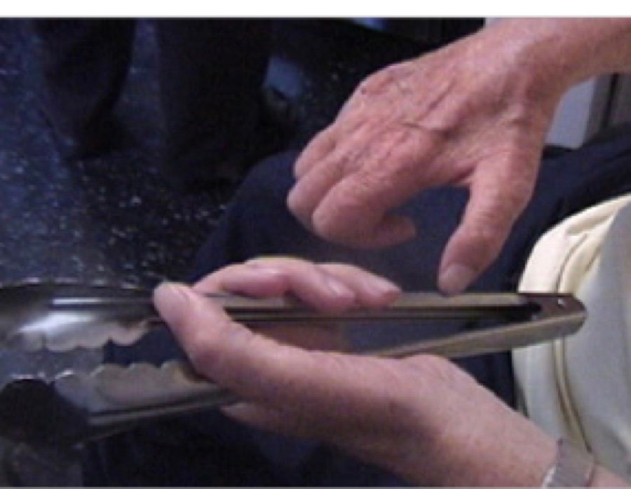 A man using kitchen tongs to make up for limited grip strength